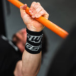 Hand holding an orange bar with a black wrist support featuring white text.