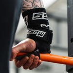 Person wearing a wrist wrap with a visible brand logo, holding an orange barbell.