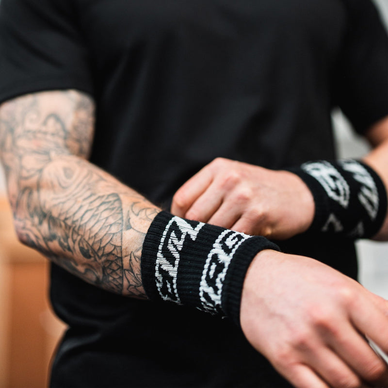 Person wearing black wrist wraps with white text on a blurred background