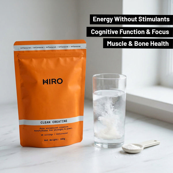 Orange package of HIRO Clean Creatine with a glass of water and scoop on a light surface.