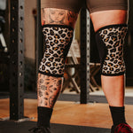 Person wearing leopard print knee sleeves in a gym setting