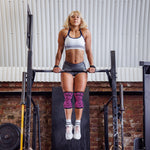 Woman performing pull-ups on a bar in a gym setting.