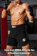 Man wearing black MMA shorts with visible brand logos in a training setting.